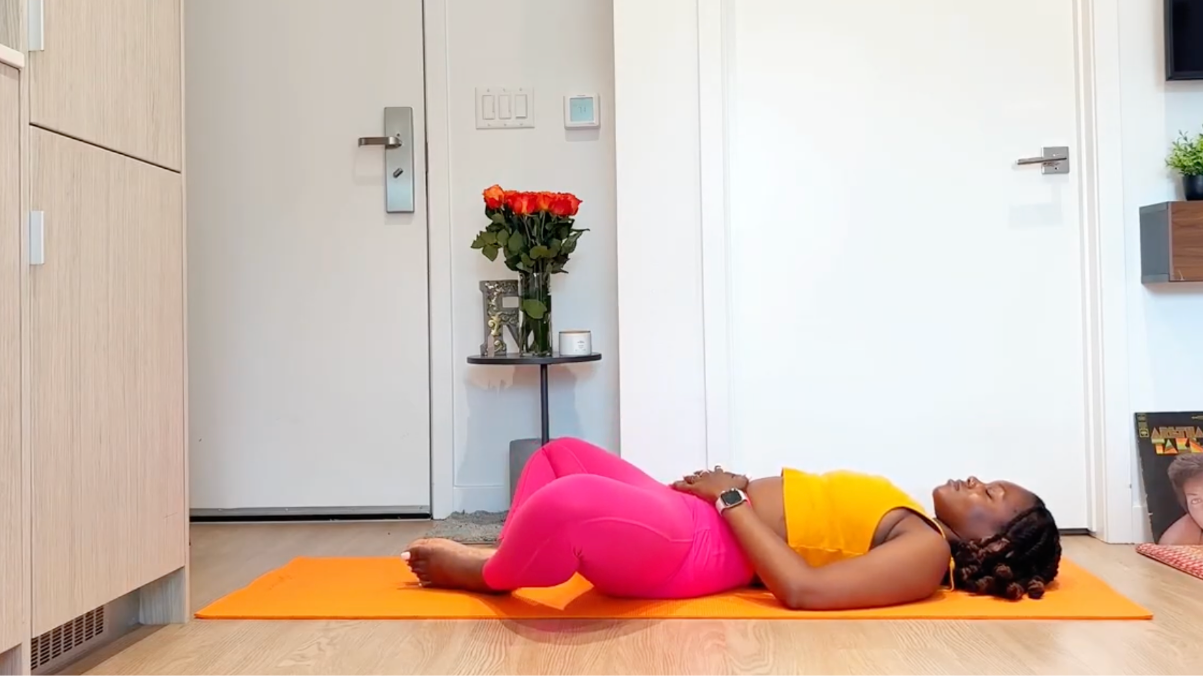 A yoga teacher practices a restricted angle reclining pose.